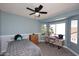 This bedroom features light blue walls, a ceiling fan, a work space, and natural light from the windows at 4338 E Towne Ln, Gilbert, AZ 85234