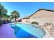 Backyard pool featuring a rock waterfall, palm trees, and clear blue water under a sunny sky at 4338 E Towne Ln, Gilbert, AZ 85234