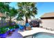 Backyard patio and pool area with blue chairs, palm trees, and a dark metal fence at 4338 E Towne Ln, Gilbert, AZ 85234