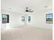 Spacious and light-filled living room featuring neutral carpet, black window frames, and ceiling fan at 8147 E Redberry --, Mesa, AZ 85207