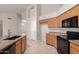 Well-lit kitchen with granite countertops, black appliances, wooden cabinetry, and a center island with sink at 1182 E Harrison St, Gilbert, AZ 85295