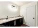 Bright bathroom featuring double sinks, black cabinets, granite counters, and modern fixtures at 12056 W Melinda Ln, Sun City, AZ 85373