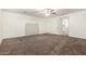 Empty carpeted bedroom with ceiling fan, neutral paint, doorway, and a window for natural light at 12056 W Melinda Ln, Sun City, AZ 85373