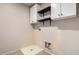 Functional laundry room with white cabinets, open shelving, and a utility sink at 12056 W Melinda Ln, Sun City, AZ 85373