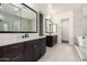 Elegant bathroom featuring dual vanities, decorative mirrors, tiled floors, and a glass shower enclosure at 1331 E La Mirada Dr, Phoenix, AZ 85042