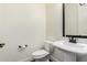 Small half-bath features a white pedestal sink, toilet, and dark framed mirror at 1331 E La Mirada Dr, Phoenix, AZ 85042