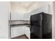 Bright kitchen features white cabinets, dark countertops, wood-look tile flooring, and black refrigerator at 1331 E La Mirada Dr, Phoenix, AZ 85042