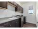 Laundry room area with dark cabinets and stainless steel washing and drying machines at 1331 E La Mirada Dr, Phoenix, AZ 85042