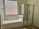 Bathroom featuring a tub with glass block window and a glass-enclosed shower at 13542 W Port Au Prince Ln, Surprise, AZ 85379