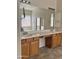 Bathroom featuring double sinks, wooden cabinets, and a large mirror at 13542 W Port Au Prince Ln, Surprise, AZ 85379