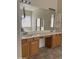 Bathroom featuring double sinks, wooden cabinets, and a large mirror at 13542 W Port Au Prince Ln, Surprise, AZ 85379