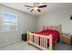 Bright bedroom with a wooden bed frame, fan, and a view from the window at 15658 W Cortez St, Surprise, AZ 85379