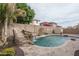 Beautiful backyard featuring a sparkling pool with a rock waterfall and mature trees at 15658 W Cortez St, Surprise, AZ 85379