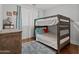 A cozy bedroom with a bunk bed frame, a wooden dresser, wood flooring, and plenty of natural light at 16533 W Carmen Dr, Surprise, AZ 85388