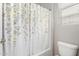 Bathroom featuring a shower-tub combo with a floral curtain and white toilet and window at 16771 W Adams St, Goodyear, AZ 85338