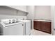 Modern laundry room with white washer and dryer and dark cabinets and countertops at 16771 W Adams St, Goodyear, AZ 85338