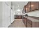 Kitchen area with wood cabinetry, tile floors, and adjacent pantry at 17008 W Sonora St, Goodyear, AZ 85338