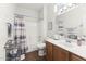 A bathroom featuring a wooden vanity, toilet, and shower/tub combination with a patterned curtain at 18137 N Plaza Ct, Surprise, AZ 85374