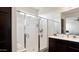 Bright bathroom featuring tile floors, a glass-enclosed shower and a dark wooden vanity at 1924 S 82Nd Cir, Mesa, AZ 85209
