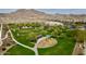 Scenic aerial view of a community park with mature trees, playground and sports fields, set against mountains at 2169 N 212Th Ln, Buckeye, AZ 85396