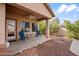 Outdoor back patio area features two blue chairs, a ceiling fan, and a gravel backyard with some foliage at 28321 N Zircon Dr, San Tan Valley, AZ 85143