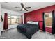 Main bedroom with a ceiling fan, large window, and red accent wall at 28321 N Zircon Dr, San Tan Valley, AZ 85143