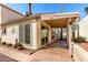 The covered backyard patio with brick tiling features desert landscaping and sliding glass door access at 448 E Wescott Dr, Phoenix, AZ 85024