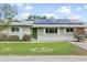Charming single-story home featuring a green front door, fresh landscaping, and solar panels at 4938 W Tuckey Ln, Glendale, AZ 85301
