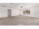 This expansive living room features plush carpeting, a ceiling fan, and a bright window at 5038 W Acoma Dr, Glendale, AZ 85306