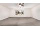 Spacious living room showcasing carpet flooring, a ceiling fan, and a bright window at 5038 W Acoma Dr, Glendale, AZ 85306