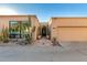 Desert home boasts tan stucco, lush xeriscaping, arched front door, and attached two car garage at 5970 N Echo Canyon Dr, Phoenix, AZ 85018