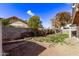Backyard features a grass area, a patio, a stone wall, and shady trees, providing a peaceful outdoor space at 6925 W Maldonado Rd, Laveen, AZ 85339