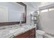 Bathroom with a granite countertop, white toilet, and shower area enclosed with marble-look tiles at 6925 W Maldonado Rd, Laveen, AZ 85339