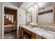 Bright bathroom with double sinks, mirrors, and a view into an adjacent bedroom at 902 W Glendale Ave # 115, Phoenix, AZ 85021