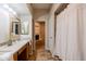 Bathroom featuring a double sink vanity with tile flooring and shower/tub combo with tile surround and white shower curtain at 902 W Glendale Ave # 115, Phoenix, AZ 85021