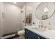 Stylish bathroom with a glass shower, blue vanity with gold hardware, and decorative round mirror at 16013 N 111Th Pl, Scottsdale, AZ 85255