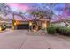 Attractive home exterior featuring a well-manicured desert landscape, mature trees and a dark garage door at 16013 N 111Th Pl, Scottsdale, AZ 85255