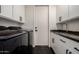 Laundry room with modern appliances, white cabinets, black hardware, and a sleek countertop sink at 16013 N 111Th Pl, Scottsdale, AZ 85255
