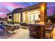 An expansive patio features an outdoor kitchen, dining area, and comfortable seating under a colorful sunset sky at 16013 N 111Th Pl, Scottsdale, AZ 85255