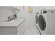 Bright laundry room with white cabinets, sink, counter space and modern washer and dryer at 1721 E Hatcher Dr, Phoenix, AZ 85020