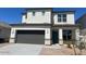 Two-story home featuring a gray garage door and neutral stucco exterior with stone accents at 17648 W Sanna St, Waddell, AZ 85355