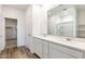 Bright bathroom with double sinks, quartz countertop, white cabinets, and views to other rooms at 17704 W Mission Ln, Waddell, AZ 85355