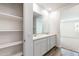 Elegant bathroom with double sinks, white cabinetry, and wood-look flooring with access to bedroom and storage at 17704 W Mission Ln, Waddell, AZ 85355