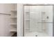 Modern bath featuring tiled shower with clear glass door and built-in shelves, next to storage closet at 17704 W Mission Ln, Waddell, AZ 85355