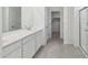 Modern bathroom with white vanity, large mirror, and walk-in closet access at 17744 W Hatcher Rd, Waddell, AZ 85355