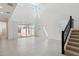 Bright living room with soaring ceilings, sliding glass doors, neutral tile flooring, and a carpeted staircase at 17744 W Hatcher Rd, Waddell, AZ 85355