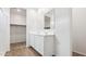 Bright bathroom boasts double sinks, white cabinets and a large mirror connecting to the walk-in closet at 18377 W Gray Fox Trl, Wittmann, AZ 85361