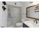 Well-lit bathroom featuring a glass-enclosed shower and modern sink with a wood-trimmed mirror at 8410 N 32Nd Ave, Phoenix, AZ 85051