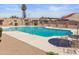 A community pool with an umbrella and table set, surrounded by sand and palm trees at 8410 N 32Nd Ave, Phoenix, AZ 85051