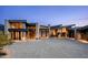 Modern home with stone accents, large windows and a spacious driveway behind a gated entry at dusk at 9643 E Cintarosa Pass, Scottsdale, AZ 85262